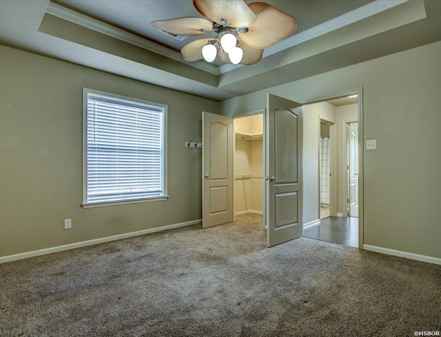 unfurnished bedroom with ornamental molding, a raised ceiling, light carpet, and baseboards