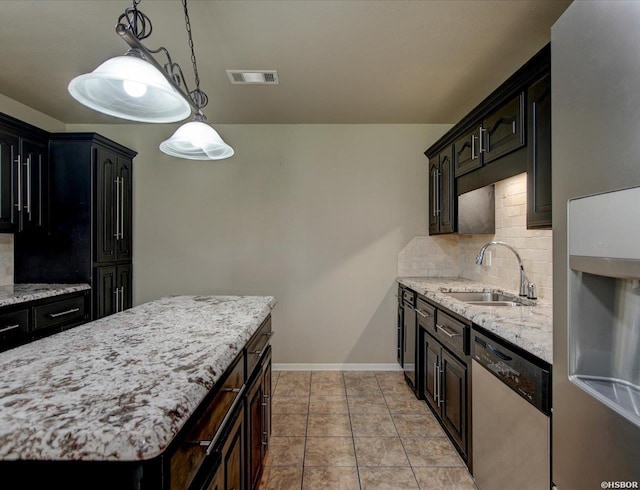 kitchen featuring light tile patterned floors, dishwasher, backsplash, decorative light fixtures, and a sink