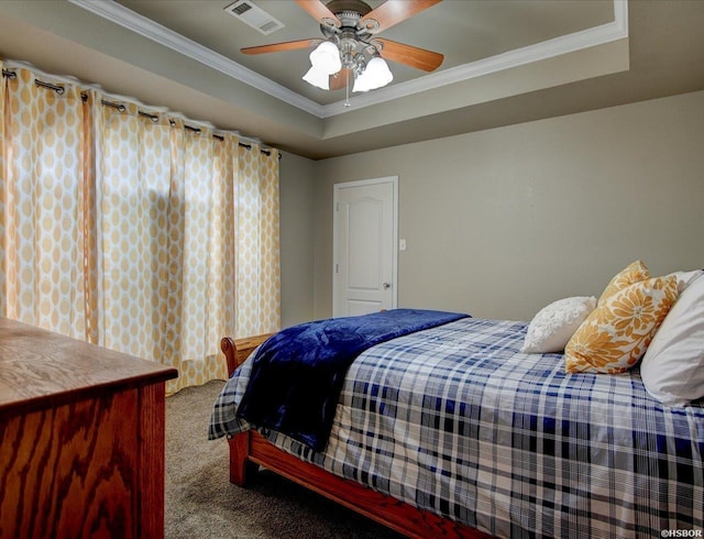 carpeted bedroom with ornamental molding, a tray ceiling, visible vents, and ceiling fan