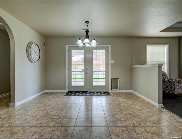 doorway featuring arched walkways, light tile patterned flooring, visible vents, and a healthy amount of sunlight