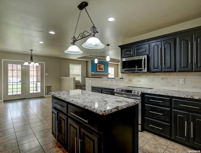 kitchen featuring open floor plan, appliances with stainless steel finishes, pendant lighting, and a center island