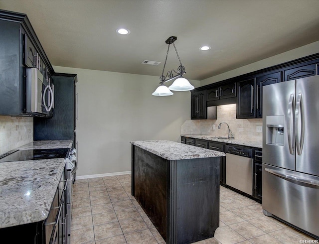 kitchen with tasteful backsplash, appliances with stainless steel finishes, a center island, pendant lighting, and a sink