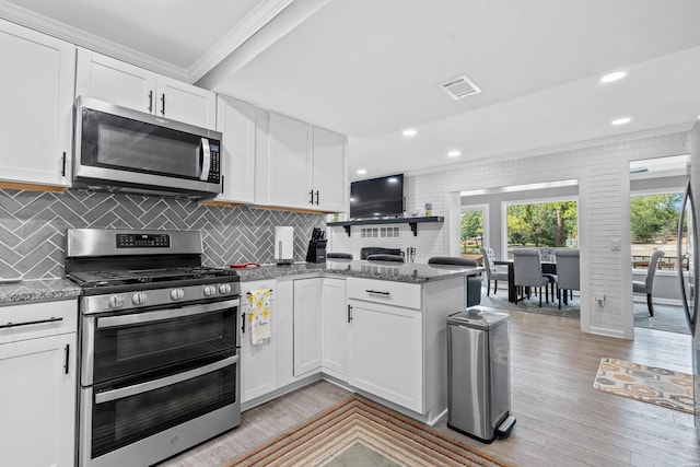 kitchen with stainless steel appliances, light wood finished floors, stone counters, and white cabinetry