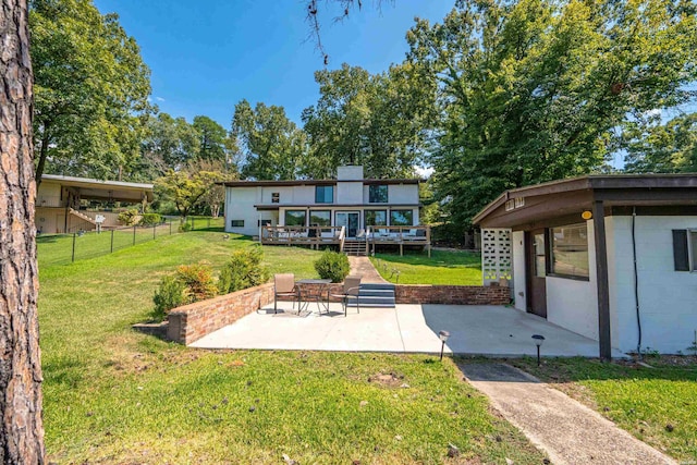 rear view of property with concrete block siding, a patio area, a lawn, and fence