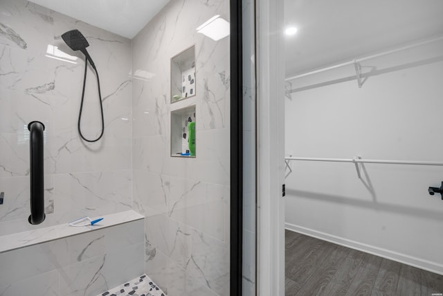 bathroom with baseboards, a marble finish shower, and wood finished floors