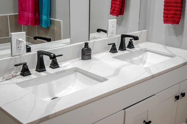 full bathroom with double vanity and a sink