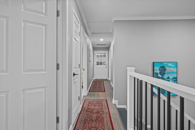 hall with ornamental molding, attic access, baseboards, and wood finished floors