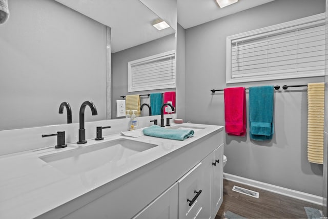 bathroom featuring wood finished floors, vanity, visible vents, and baseboards