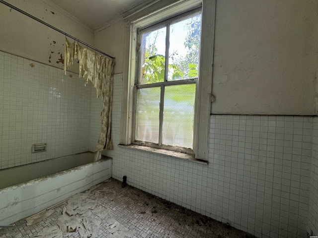 interior space with shower / bath combo, ornamental molding, tile walls, and wainscoting