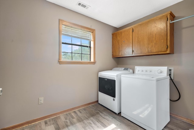 laundry area featuring cabinet space, light wood finished floors, baseboards, visible vents, and washer and dryer