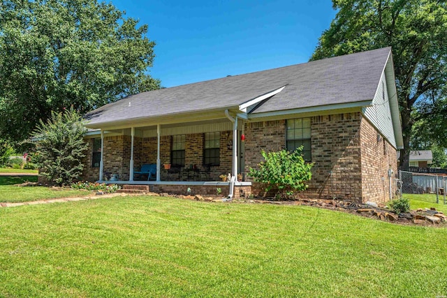 ranch-style home featuring brick siding, a front yard, and fence