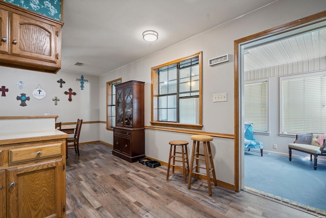 kitchen featuring brown cabinetry, wood finished floors, visible vents, and baseboards