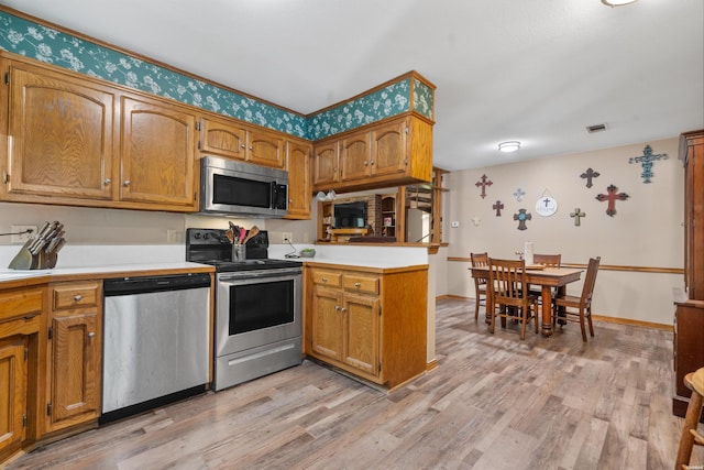 kitchen with stainless steel appliances, brown cabinetry, and light countertops