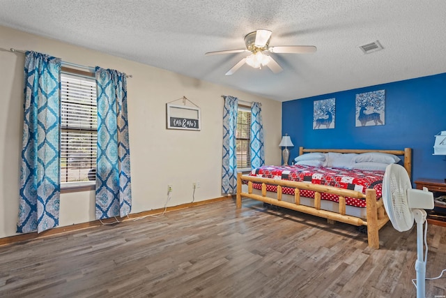 bedroom with visible vents, a textured ceiling, and wood finished floors