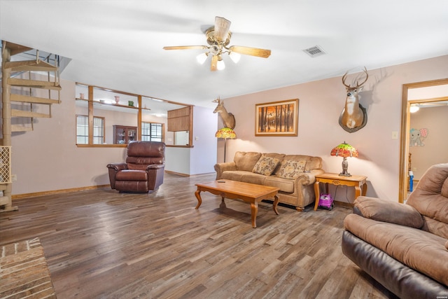 living room featuring a ceiling fan, visible vents, baseboards, and wood finished floors