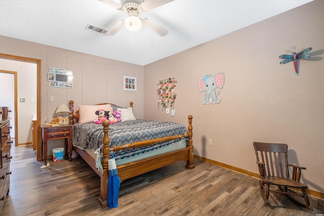 bedroom with a ceiling fan, dark wood-style flooring, visible vents, and baseboards