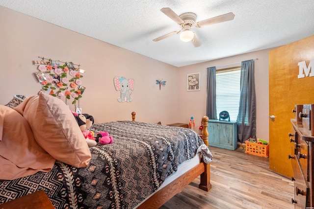 bedroom with a textured ceiling, light wood finished floors, and a ceiling fan