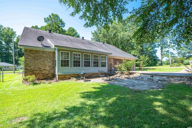 back of house featuring a yard, brick siding, a patio, and fence