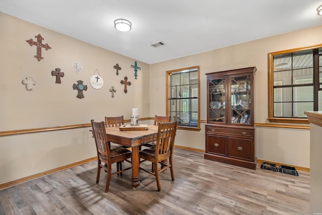 dining space with light wood-type flooring, visible vents, and baseboards