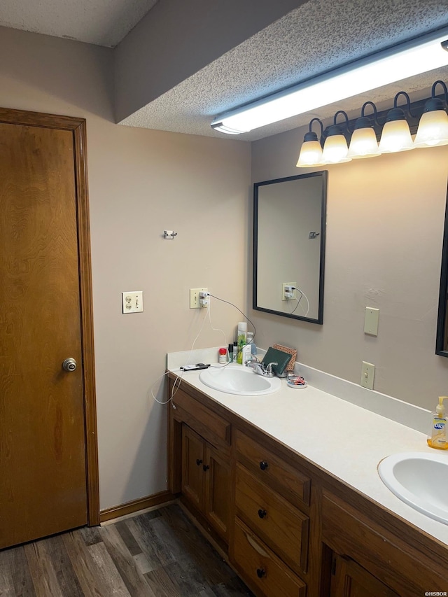 bathroom featuring double vanity, a sink, a textured ceiling, and wood finished floors