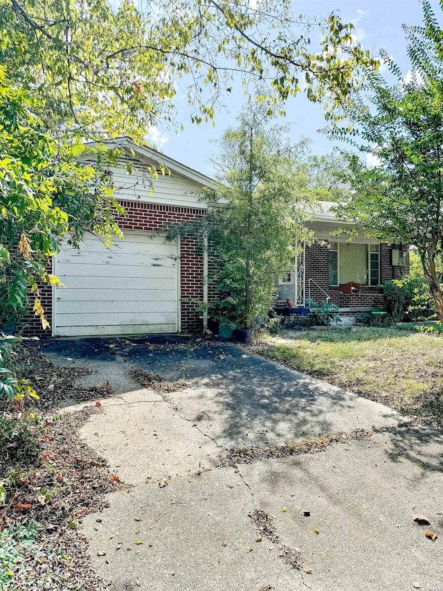 single story home with a garage, covered porch, brick siding, and driveway