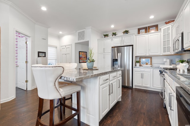 kitchen with a kitchen breakfast bar, a kitchen island, appliances with stainless steel finishes, and white cabinetry