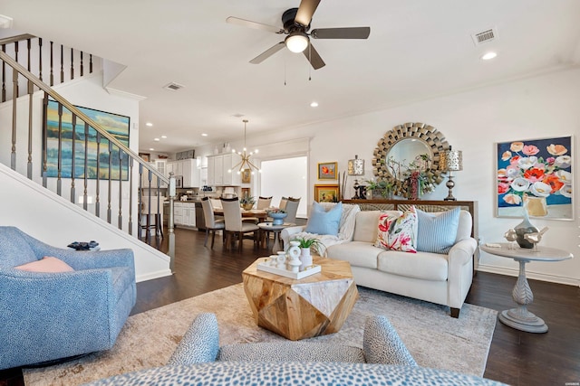 living area with visible vents, ceiling fan with notable chandelier, wood finished floors, and stairway