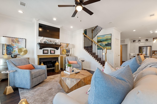 living room featuring visible vents, stairway, ceiling fan, and wood finished floors