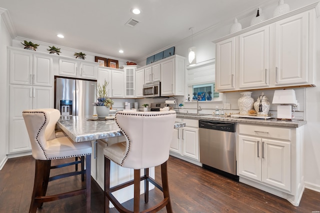 kitchen with visible vents, a sink, ornamental molding, stainless steel appliances, and white cabinetry