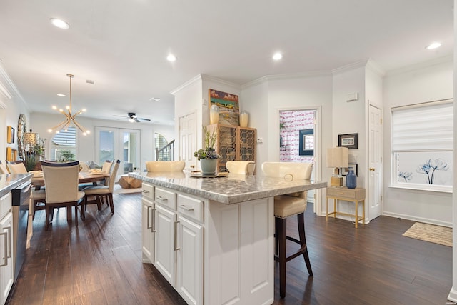 kitchen with a breakfast bar, crown molding, dark wood-style floors, and white cabinetry