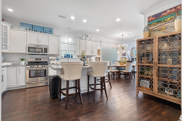 kitchen featuring white cabinetry, ornamental molding, a center island, and stainless steel appliances