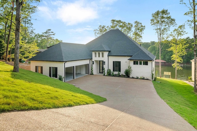 view of front of house with a garage, concrete driveway, a shingled roof, and a front lawn