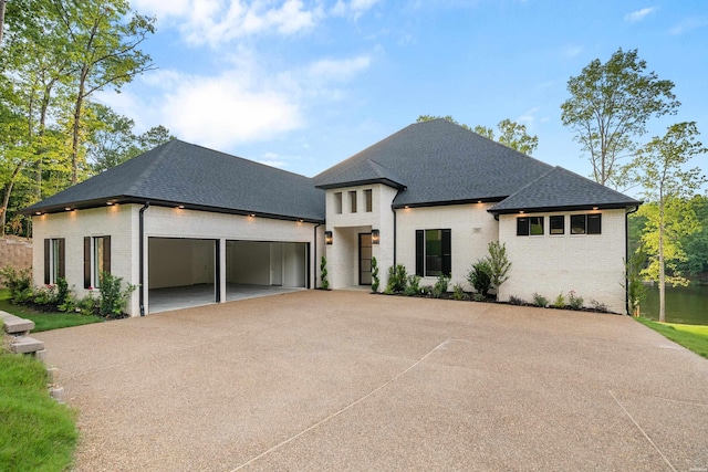 view of front of home featuring an attached garage, brick siding, and roof with shingles