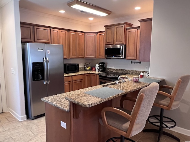 kitchen with a peninsula, light stone countertops, brown cabinets, and stainless steel appliances