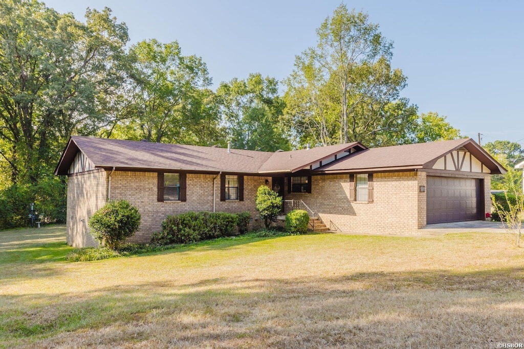 view of front facade with driveway, brick siding, an attached garage, and a front yard