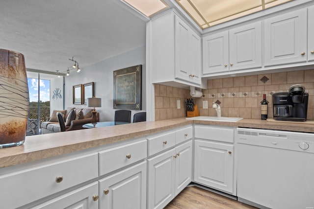 kitchen featuring white cabinets, light countertops, white dishwasher, and open floor plan