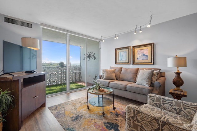 living area featuring a wall of windows, track lighting, visible vents, and dark wood-type flooring