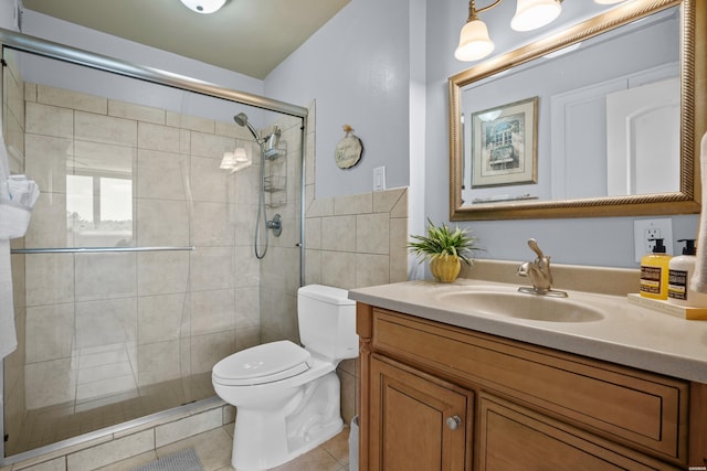 full bath featuring tile patterned flooring, a tile shower, vanity, and toilet