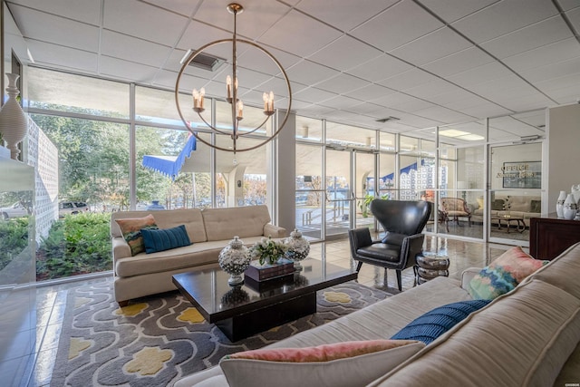 interior space with an inviting chandelier, a wall of windows, and a drop ceiling