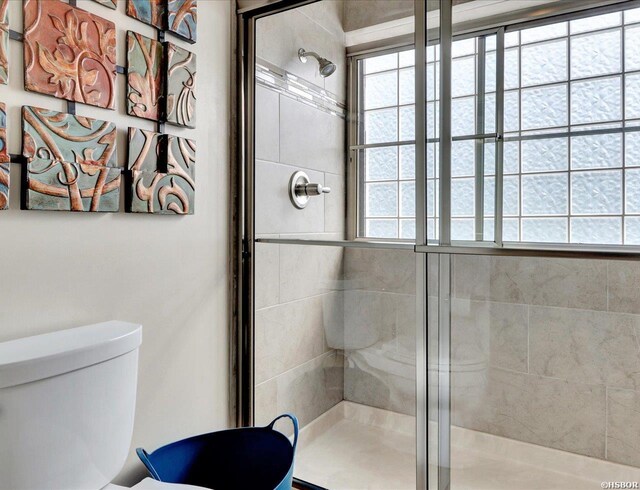 bathroom featuring toilet, a tile shower, and a wealth of natural light