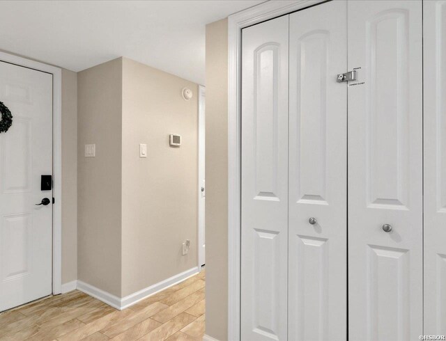 hall featuring light wood-style flooring and baseboards