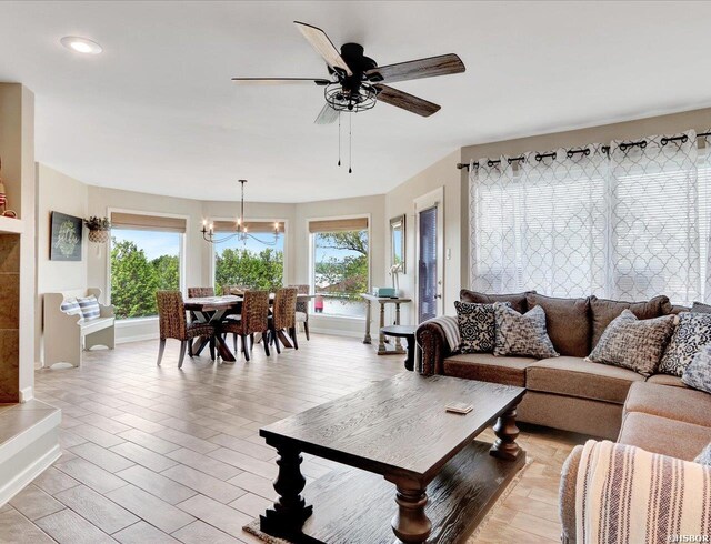 living room featuring light wood-type flooring, plenty of natural light, and ceiling fan with notable chandelier