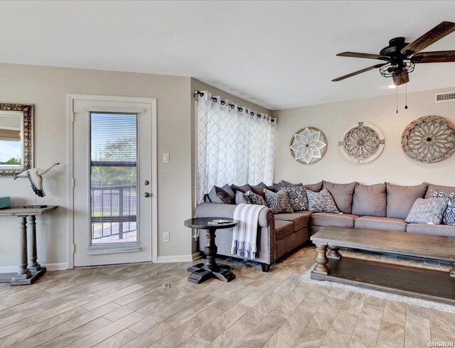 living area with light wood-style floors, visible vents, ceiling fan, and baseboards