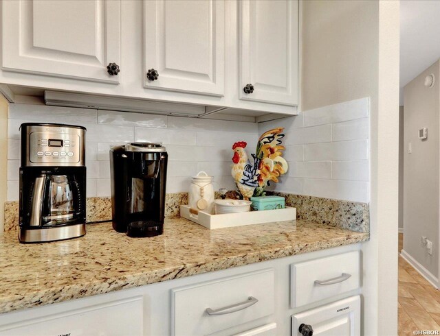 kitchen with tasteful backsplash, white cabinets, baseboards, and light stone countertops