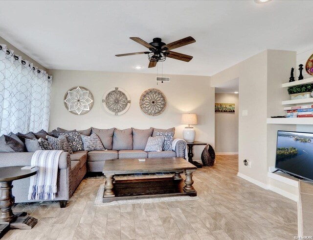 living room with visible vents, ceiling fan, and baseboards