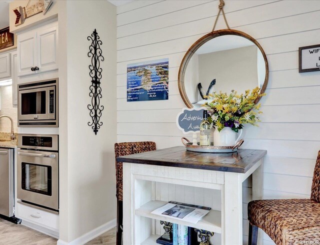 kitchen featuring dark countertops, wooden walls, white cabinetry, and stainless steel appliances