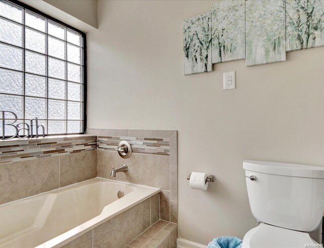 bathroom with a garden tub and toilet