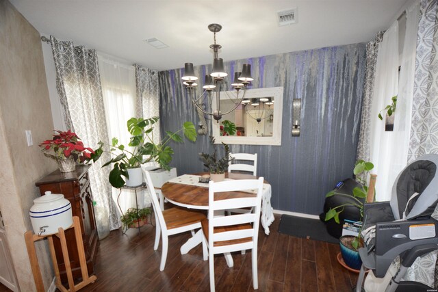 dining area with dark wood-style floors, visible vents, and a notable chandelier