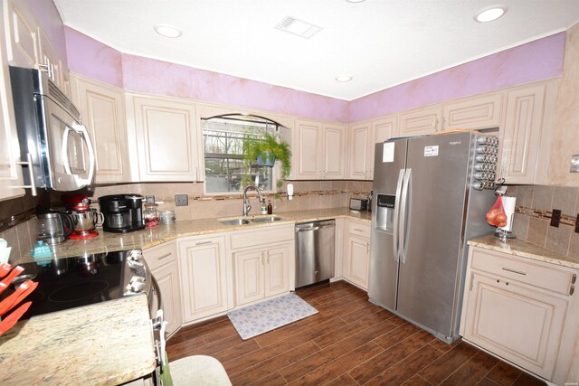 kitchen featuring appliances with stainless steel finishes, dark wood-type flooring, a sink, and light stone countertops