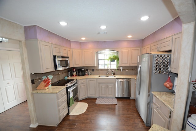 kitchen featuring a sink, visible vents, appliances with stainless steel finishes, light stone countertops, and dark wood finished floors